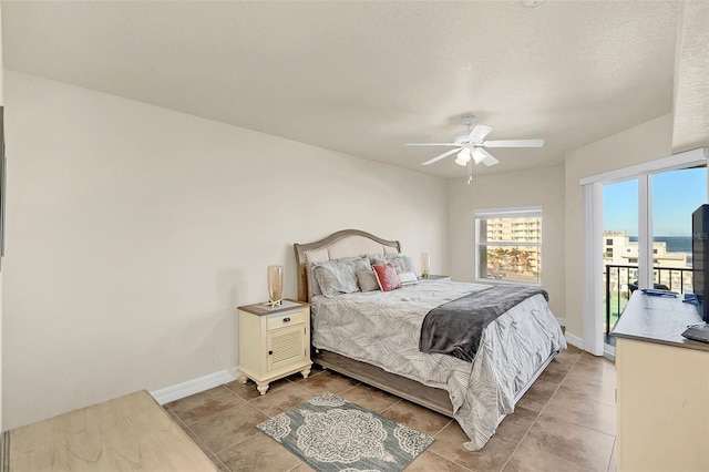 bedroom with ceiling fan, light tile patterned floors, access to outside, and a textured ceiling