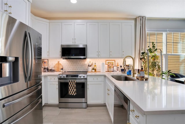 kitchen with decorative backsplash, white cabinetry, sink, and appliances with stainless steel finishes