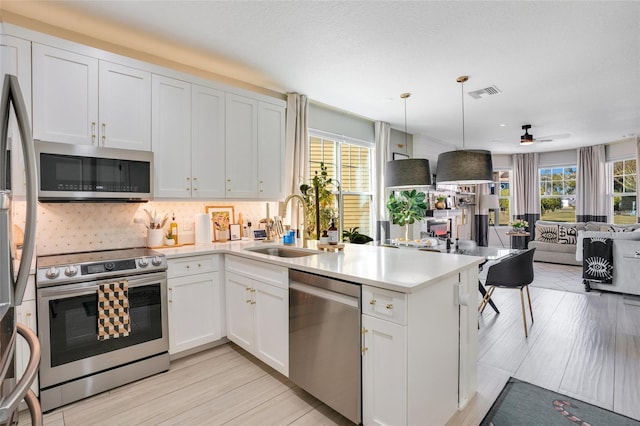 kitchen featuring decorative backsplash, appliances with stainless steel finishes, white cabinetry, and sink