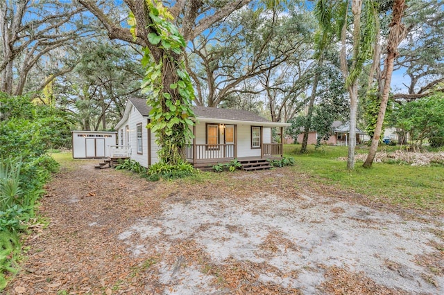 ranch-style house featuring a porch and a shed