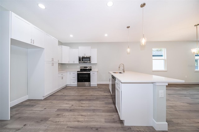 kitchen featuring stainless steel appliances, white cabinetry, sink, and pendant lighting