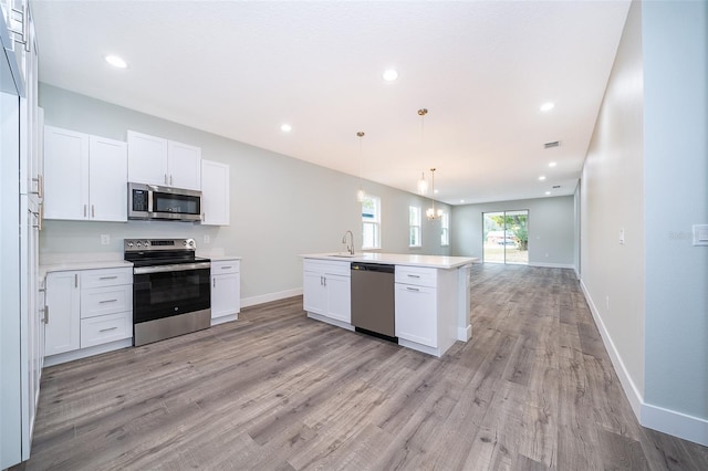 kitchen with sink, stainless steel appliances, hanging light fixtures, and white cabinetry