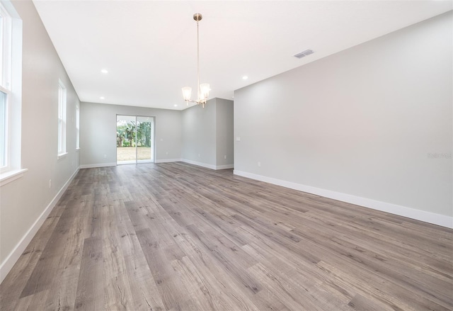 spare room featuring a notable chandelier and light hardwood / wood-style flooring