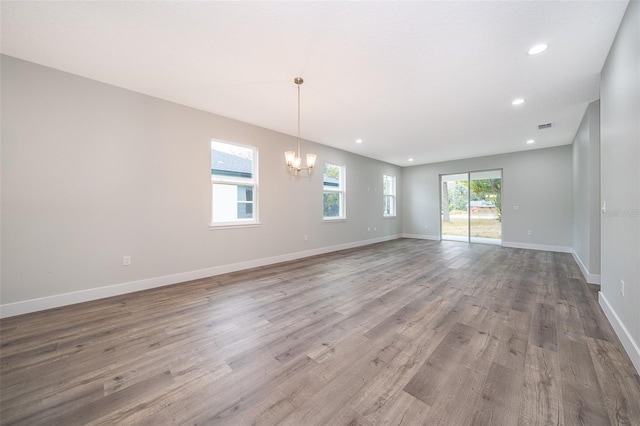 empty room with light wood-type flooring and an inviting chandelier