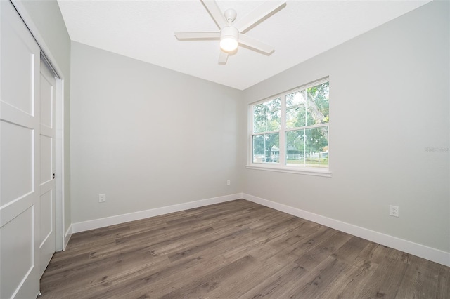 unfurnished bedroom with ceiling fan, dark wood-type flooring, and a closet