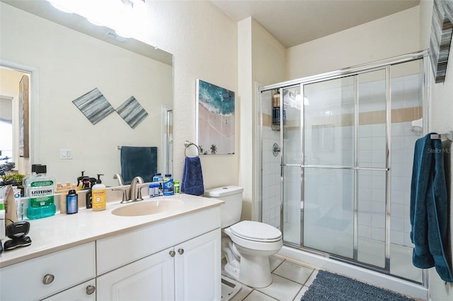 bathroom featuring tile patterned flooring, a shower with shower door, vanity, and toilet