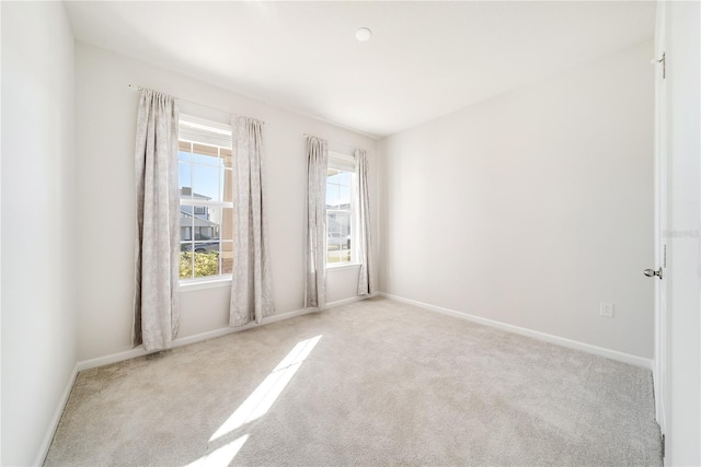 spare room featuring light colored carpet and plenty of natural light