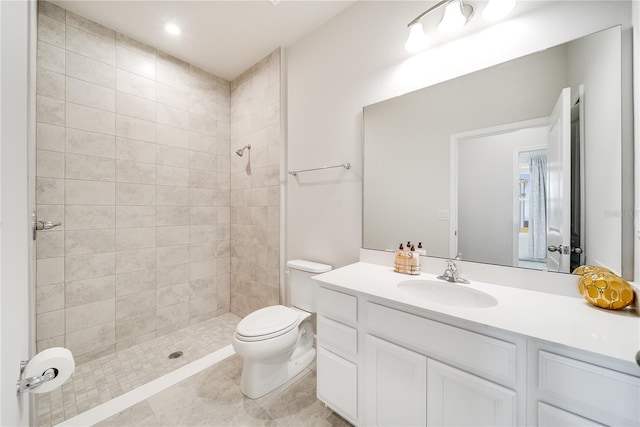 bathroom featuring toilet, tiled shower, and vanity