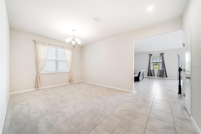 carpeted empty room with an inviting chandelier