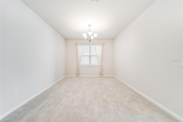 carpeted spare room with a notable chandelier