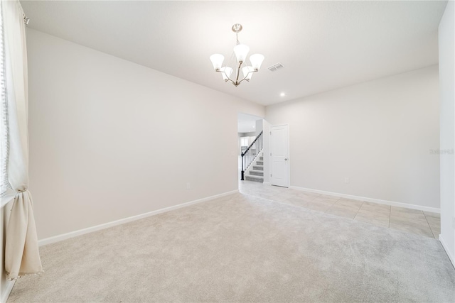 carpeted empty room with an inviting chandelier