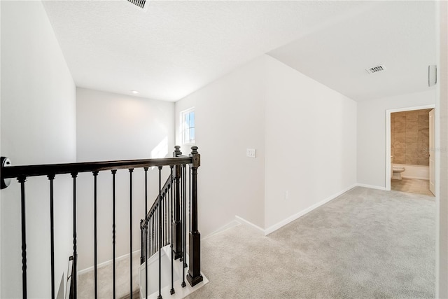 hall with a textured ceiling and light colored carpet