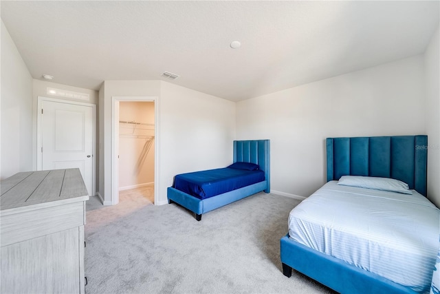 carpeted bedroom with a closet and a spacious closet