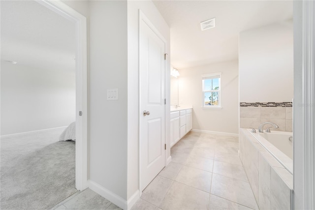 bathroom featuring tiled bath, tile patterned flooring, and vanity