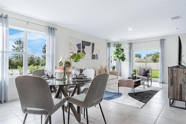 tiled dining space with a textured ceiling and plenty of natural light