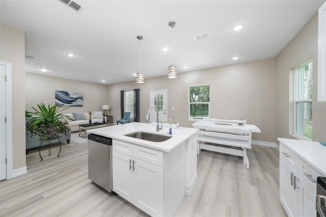 kitchen featuring white cabinets, a center island with sink, sink, stainless steel dishwasher, and decorative light fixtures