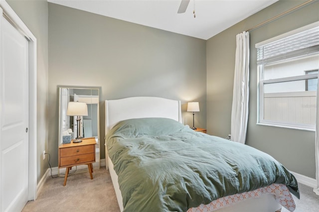 bedroom with ceiling fan, light colored carpet, and a closet