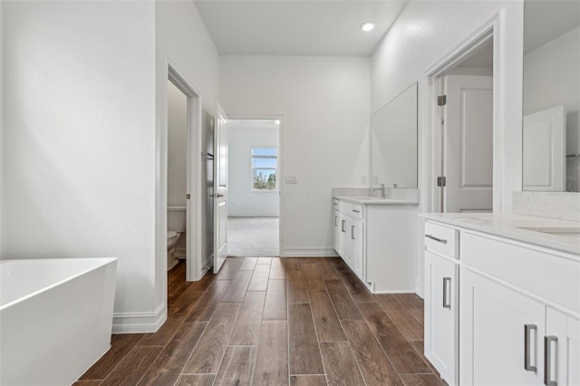 bathroom with a washtub, toilet, and vanity