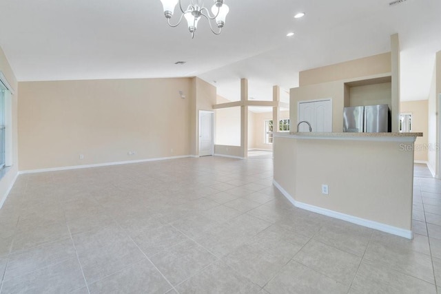 unfurnished living room featuring a notable chandelier, vaulted ceiling, and light tile patterned floors