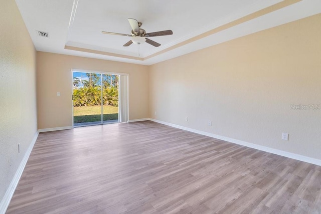 unfurnished room with light hardwood / wood-style floors, ceiling fan, and a raised ceiling