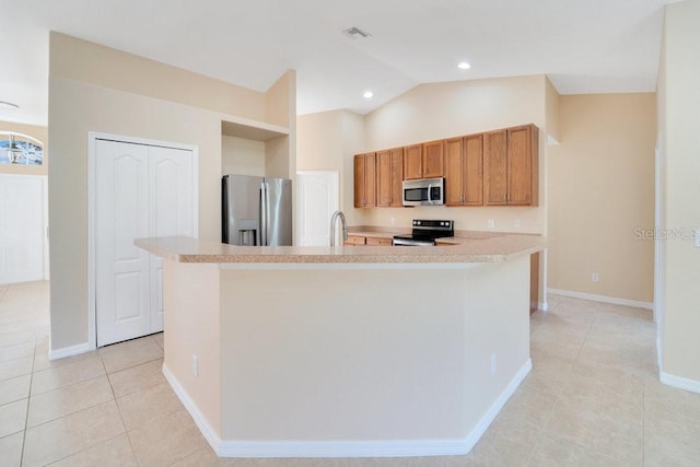 kitchen with a kitchen island with sink, vaulted ceiling, stainless steel appliances, sink, and light tile patterned flooring