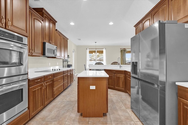 kitchen featuring light tile patterned flooring, appliances with stainless steel finishes, decorative light fixtures, sink, and a center island