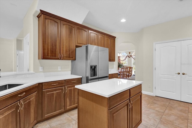 kitchen featuring sink, light tile patterned floors, stainless steel fridge, and a center island