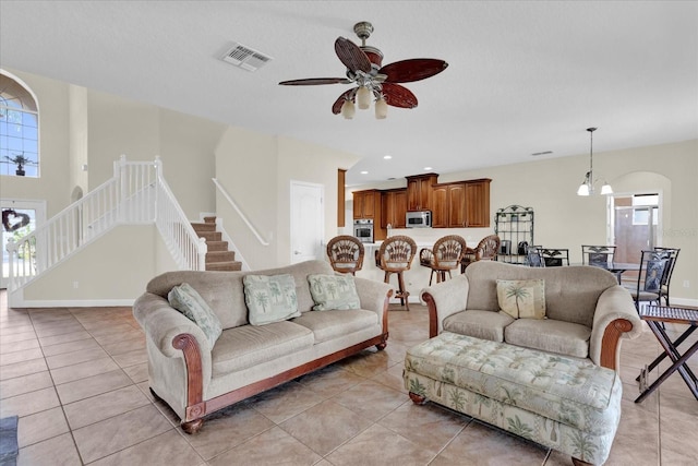 tiled living room featuring ceiling fan with notable chandelier