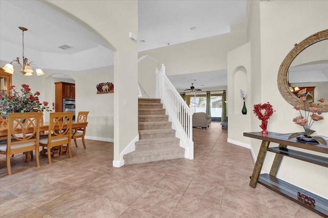 tiled entrance foyer with ceiling fan with notable chandelier