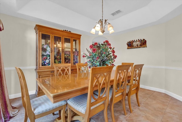 dining room with a tray ceiling, light tile patterned floors, and a notable chandelier