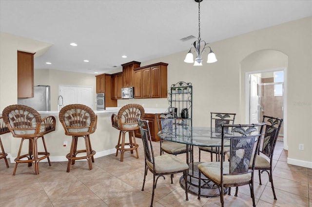 dining space with light tile patterned flooring, sink, and a chandelier