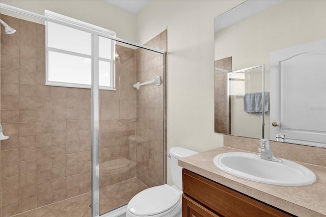 bathroom featuring vanity, toilet, and a shower with shower door