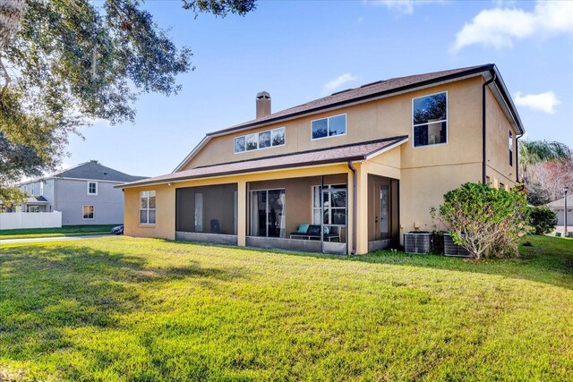 rear view of property featuring a sunroom, central air condition unit, and a lawn