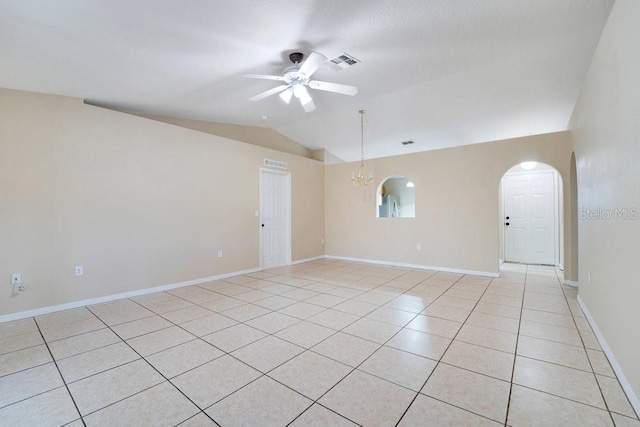 spare room featuring ceiling fan with notable chandelier, vaulted ceiling, and light tile patterned flooring