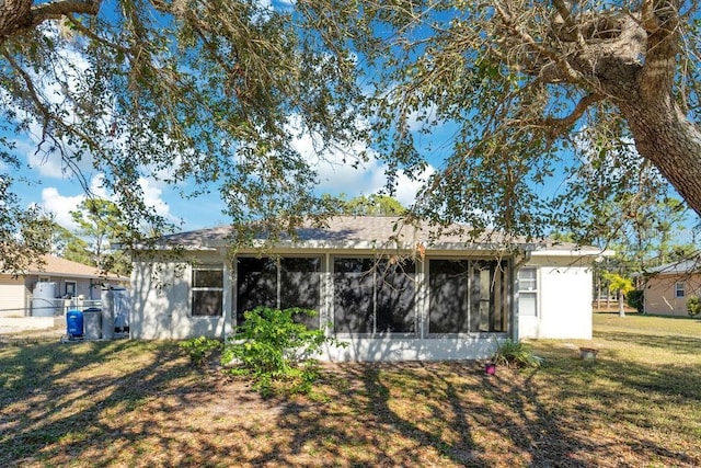 back of property with a yard and a sunroom