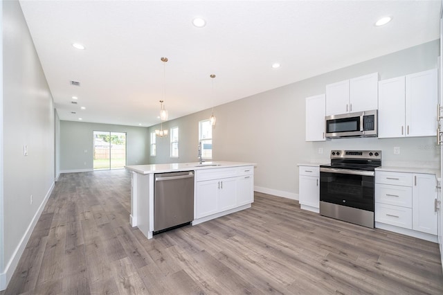 kitchen featuring appliances with stainless steel finishes, light hardwood / wood-style flooring, pendant lighting, and white cabinetry