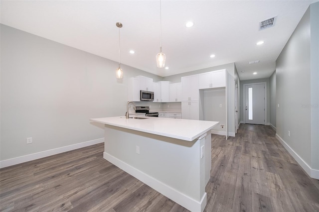 kitchen with hardwood / wood-style floors, hanging light fixtures, an island with sink, stainless steel appliances, and white cabinetry