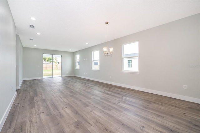 empty room featuring an inviting chandelier and light hardwood / wood-style floors