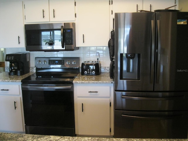 kitchen with decorative backsplash, white cabinets, stainless steel appliances, and light stone counters