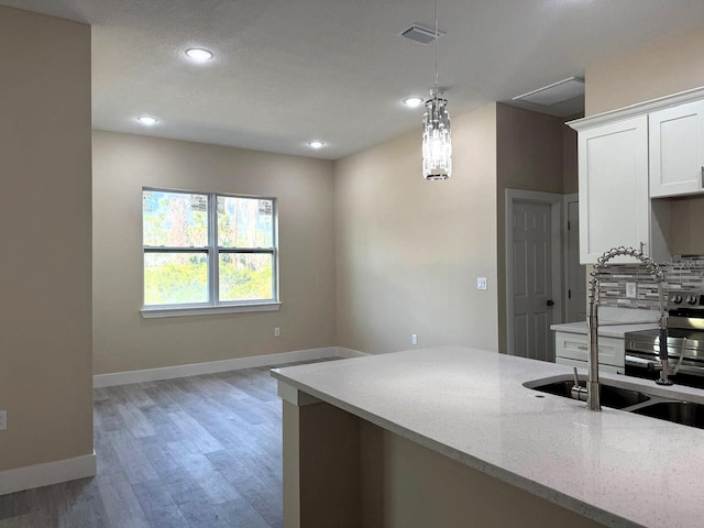 kitchen with light stone counters, baseboards, visible vents, white cabinetry, and tasteful backsplash