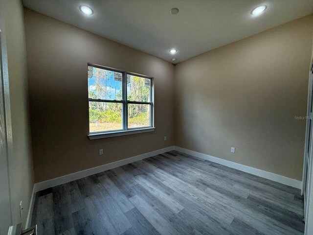 spare room with recessed lighting, baseboards, and wood finished floors