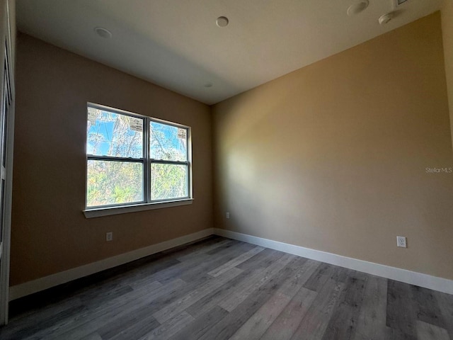 spare room with baseboards and wood finished floors