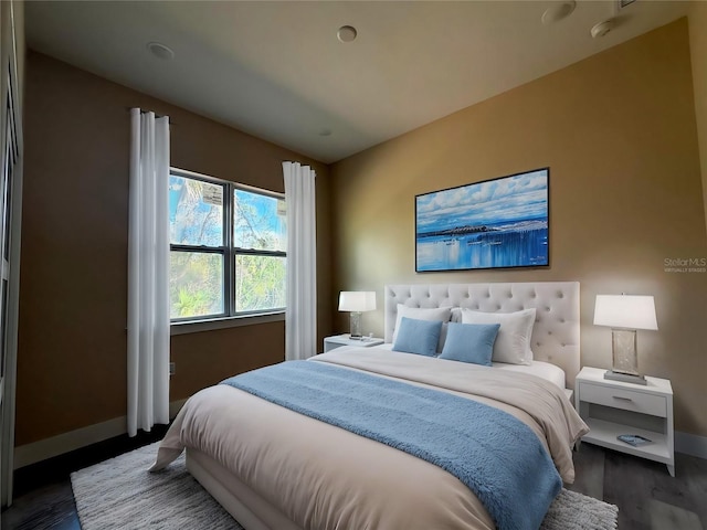 bedroom featuring lofted ceiling, wood finished floors, and baseboards