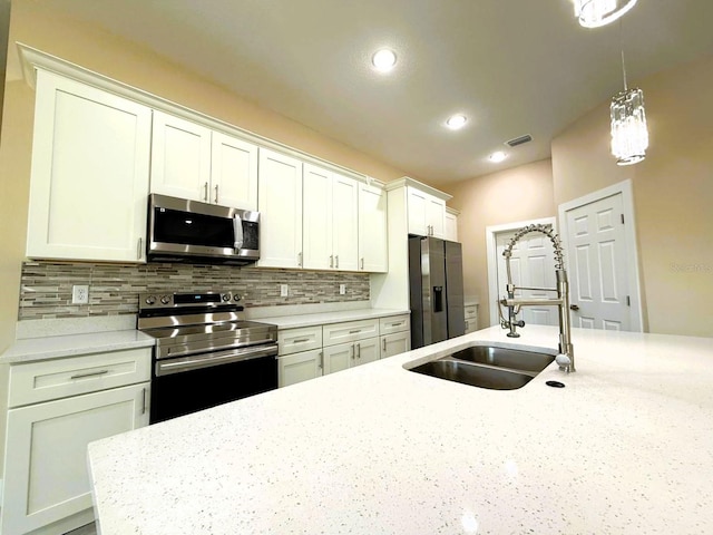 kitchen with a sink, backsplash, stainless steel appliances, white cabinets, and hanging light fixtures