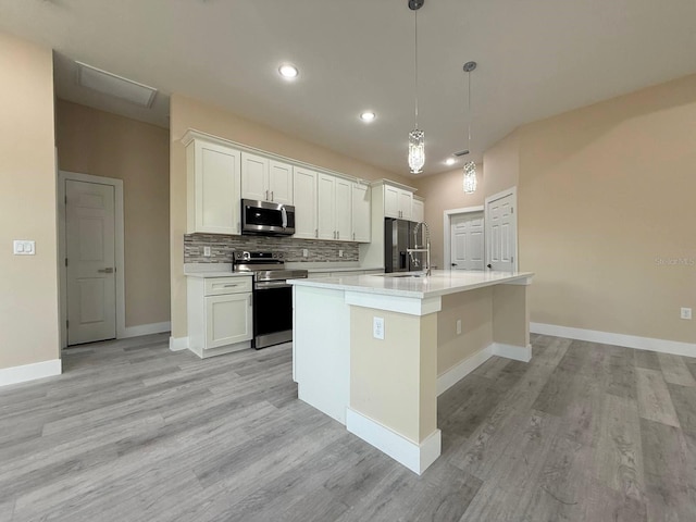 kitchen featuring a center island with sink, stainless steel appliances, white cabinets, light countertops, and decorative backsplash