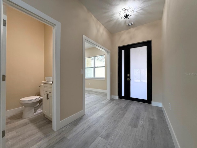 entrance foyer featuring light wood-style floors, visible vents, and baseboards