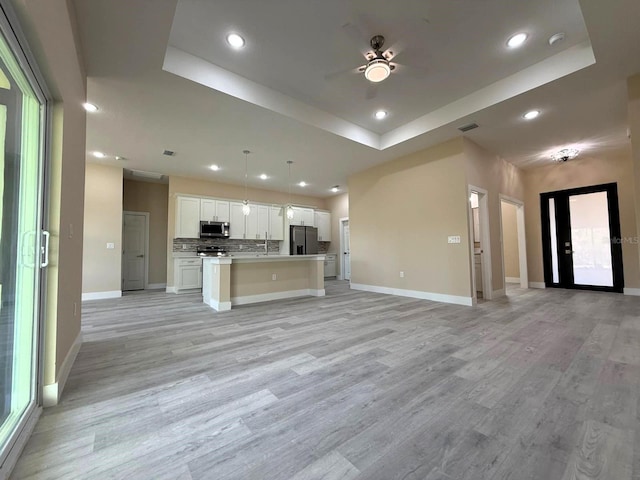 kitchen featuring a raised ceiling, appliances with stainless steel finishes, and open floor plan