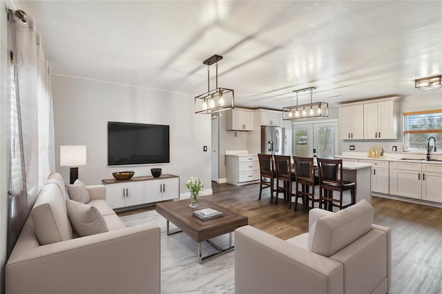 living room featuring french doors, sink, and light hardwood / wood-style flooring