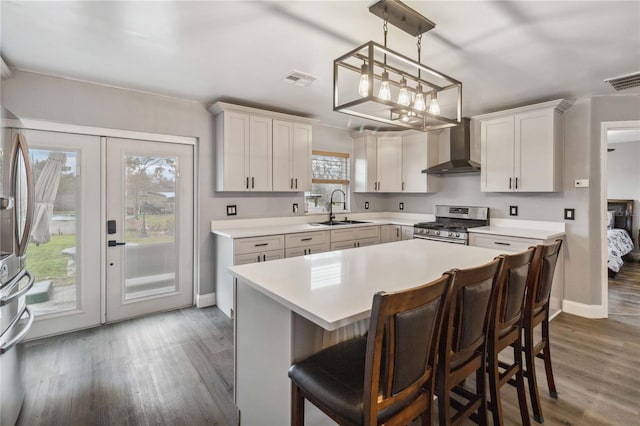 kitchen featuring wall chimney range hood, sink, stainless steel appliances, a center island, and white cabinets