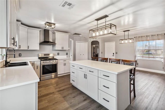 kitchen with sink, white cabinetry, a center island, gas range, and wall chimney exhaust hood